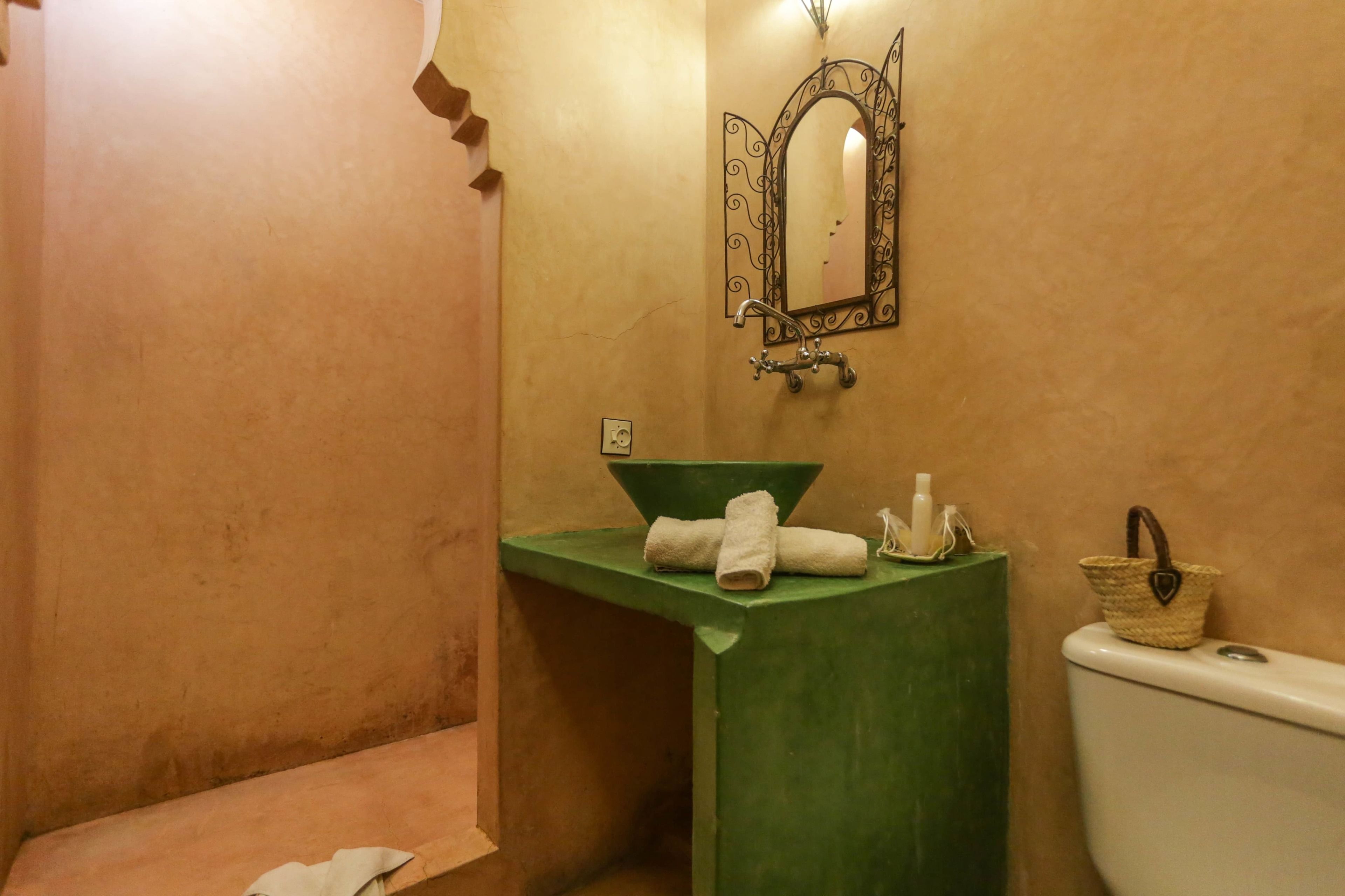 Een badkamer met een groene wastafel, een wit toilet en een spiegel met decoratieve lijst.