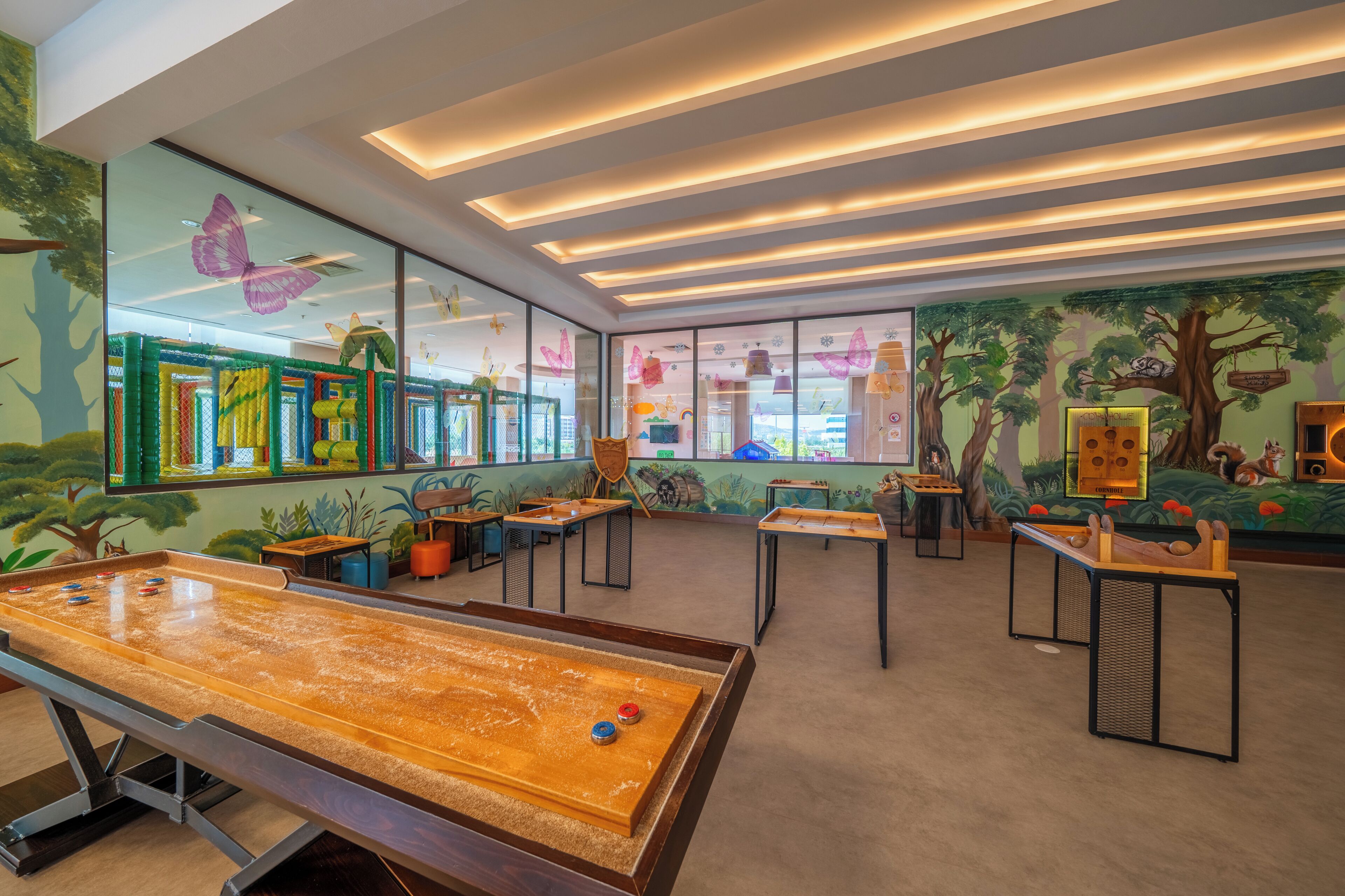 Un espace de jeux pour enfants avec des tables, des chaises et un baby-foot.