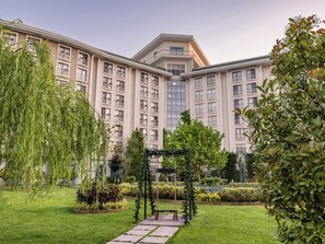 A multi-story hotel with a central courtyard, surrounded by lush greenery and a well-maintained garden. - NG Afyon (Afyonkarahisar)