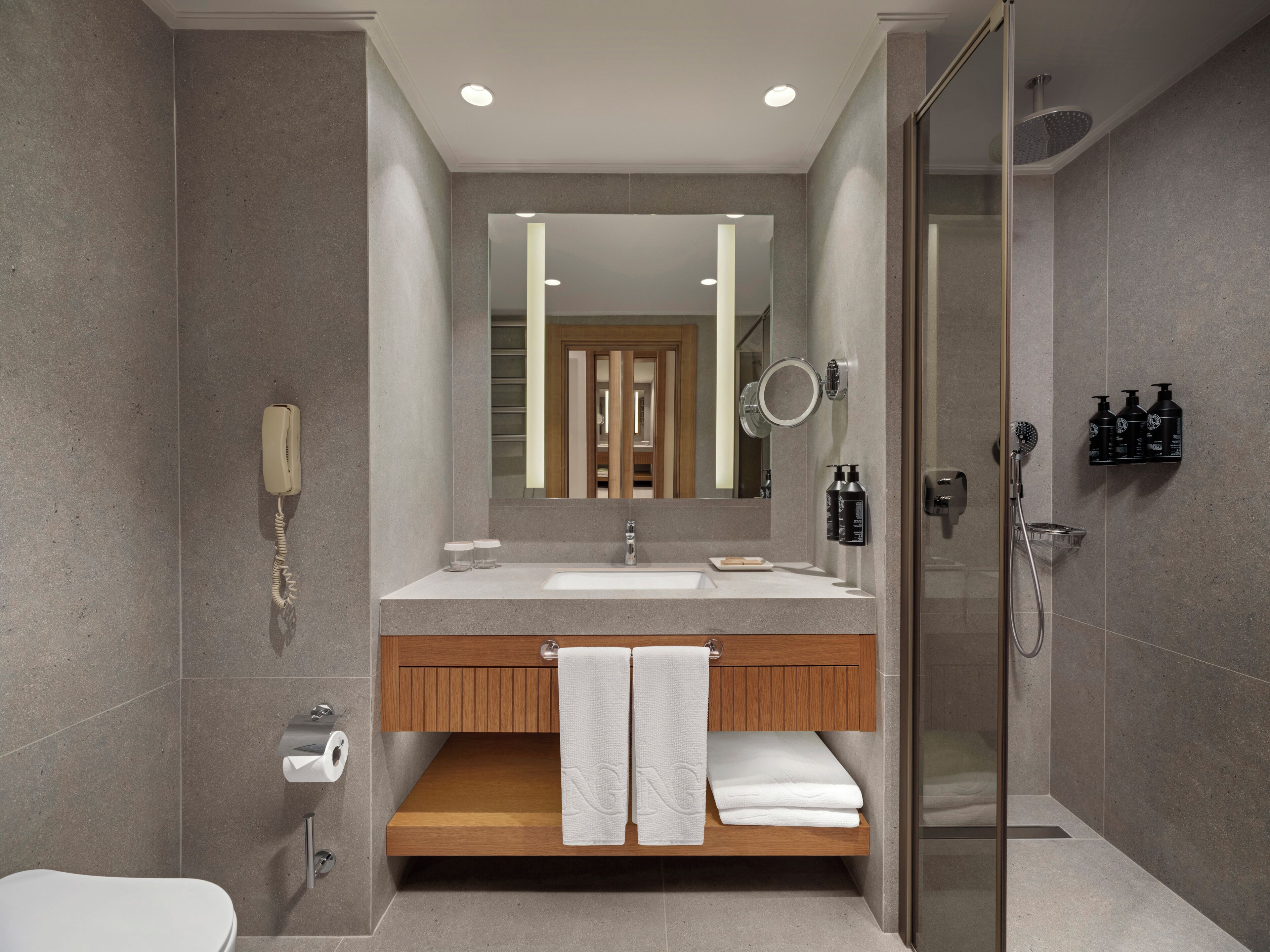 A modern bathroom with a large mirror, a shower, and a toilet.