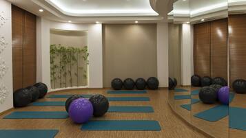 A room with exercise mats, black and purple exercise balls, and a mirror wall.