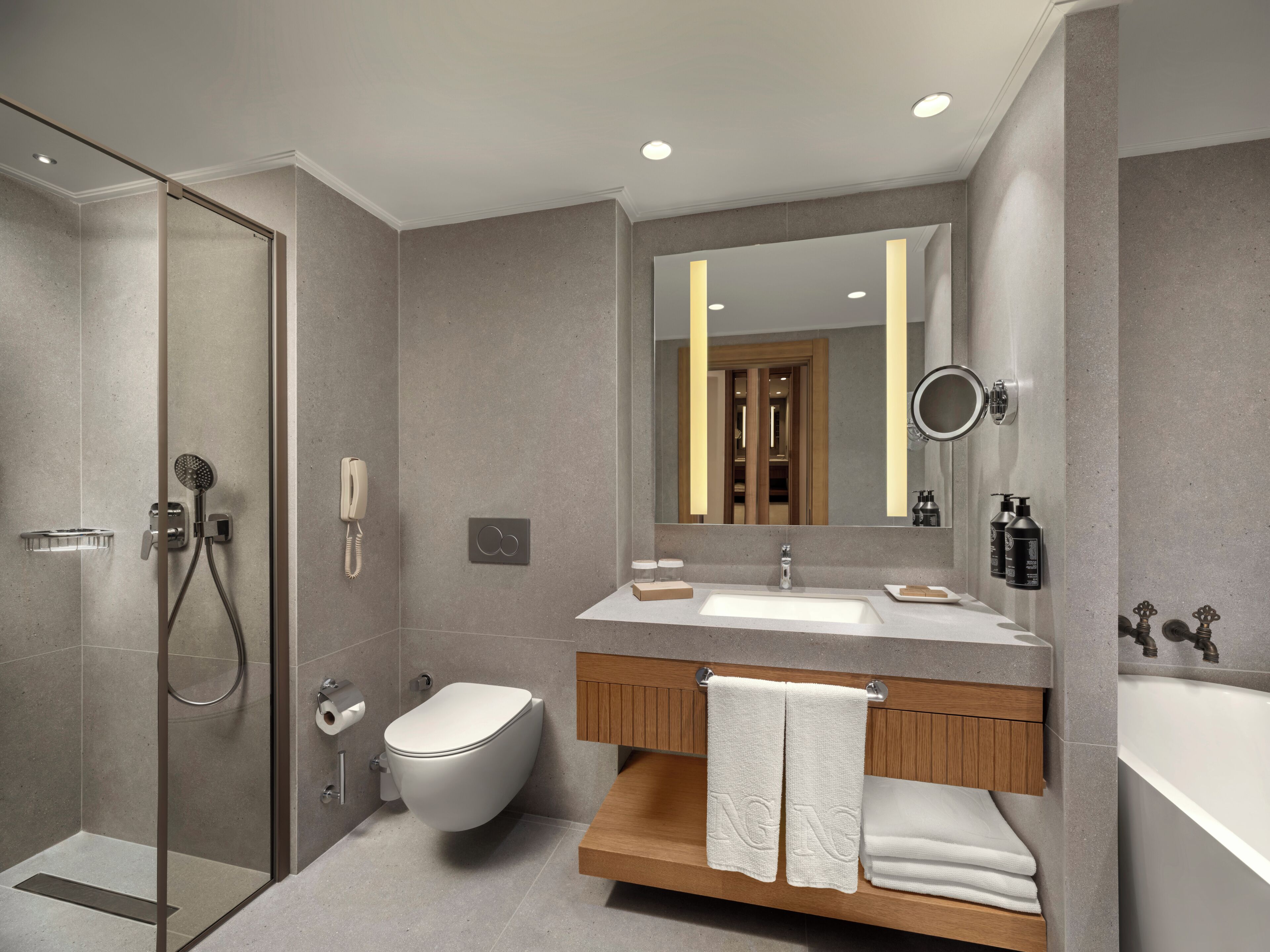 A modern bathroom with a glass-enclosed shower, a toilet, a sink with a vanity, and a large mirror.