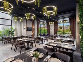 Un comedor moderno con varias mesas, sillas y lámparas circulares colgantes.