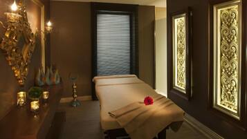 A spa room with a massage table, candles, and decorative wall panels.