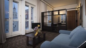 A hotel room with a large window, a sofa, a small table with a vase, and a dark wooden partition. - Bellevue (Split)