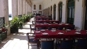 A long corridor with tables set for dining, potted plants, and a view of the street. - Bellevue (Split)