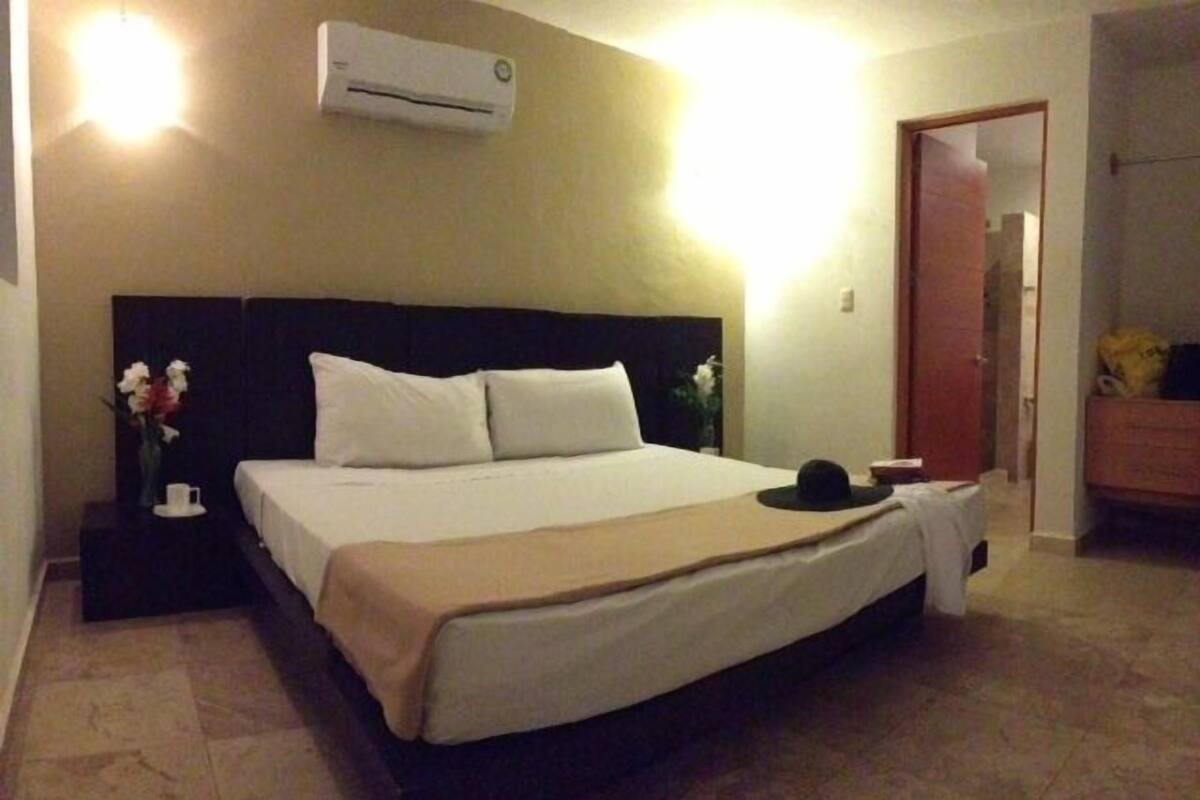 Une chambre d’hôtel comprenant un lit, une table de chevet, un climatiseur et une porte donnant sur une autre pièce.