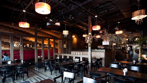 A restaurant with multiple tables and chairs, wooden panel walls, and hanging pendant lights. - Hotel Hu (Incheon)