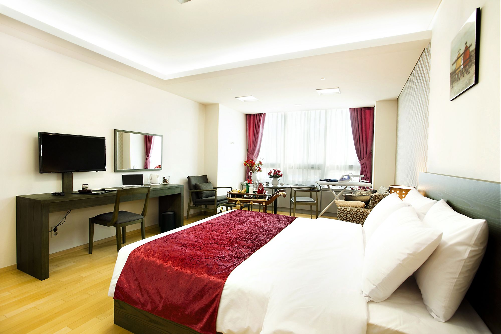 Une chambre d’hôtel comprenant un lit, un bureau avec un ordinateur, une télévision et un coin repas avec une table et des chaises.