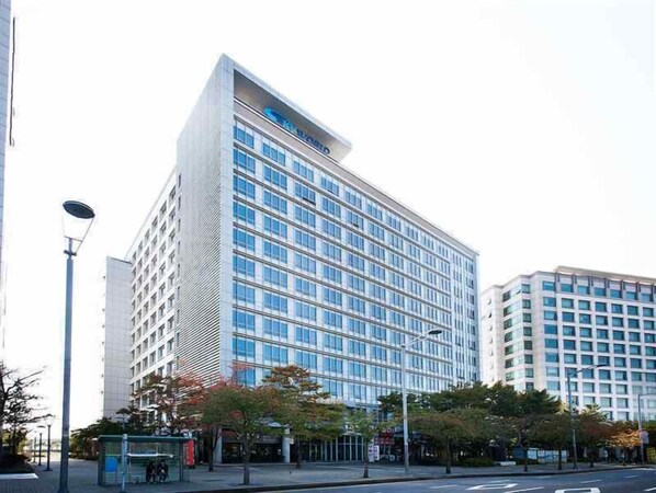 A modern high-rise hotel with a glass facade, multiple floors, and a prominent entrance.