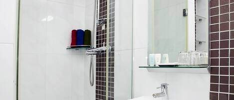 A modern bathroom with a glass-enclosed shower, a white sink, and a mirror above it.