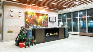 A hotel reception desk with a modern design, featuring a wooden ceiling, a large digital screen, and a reception area with a decorative Christmas tree and reindeer. - Hotel Hu (Incheon)