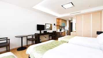 A hotel room with two beds, a desk with a computer, a chair, a TV, and a wardrobe.