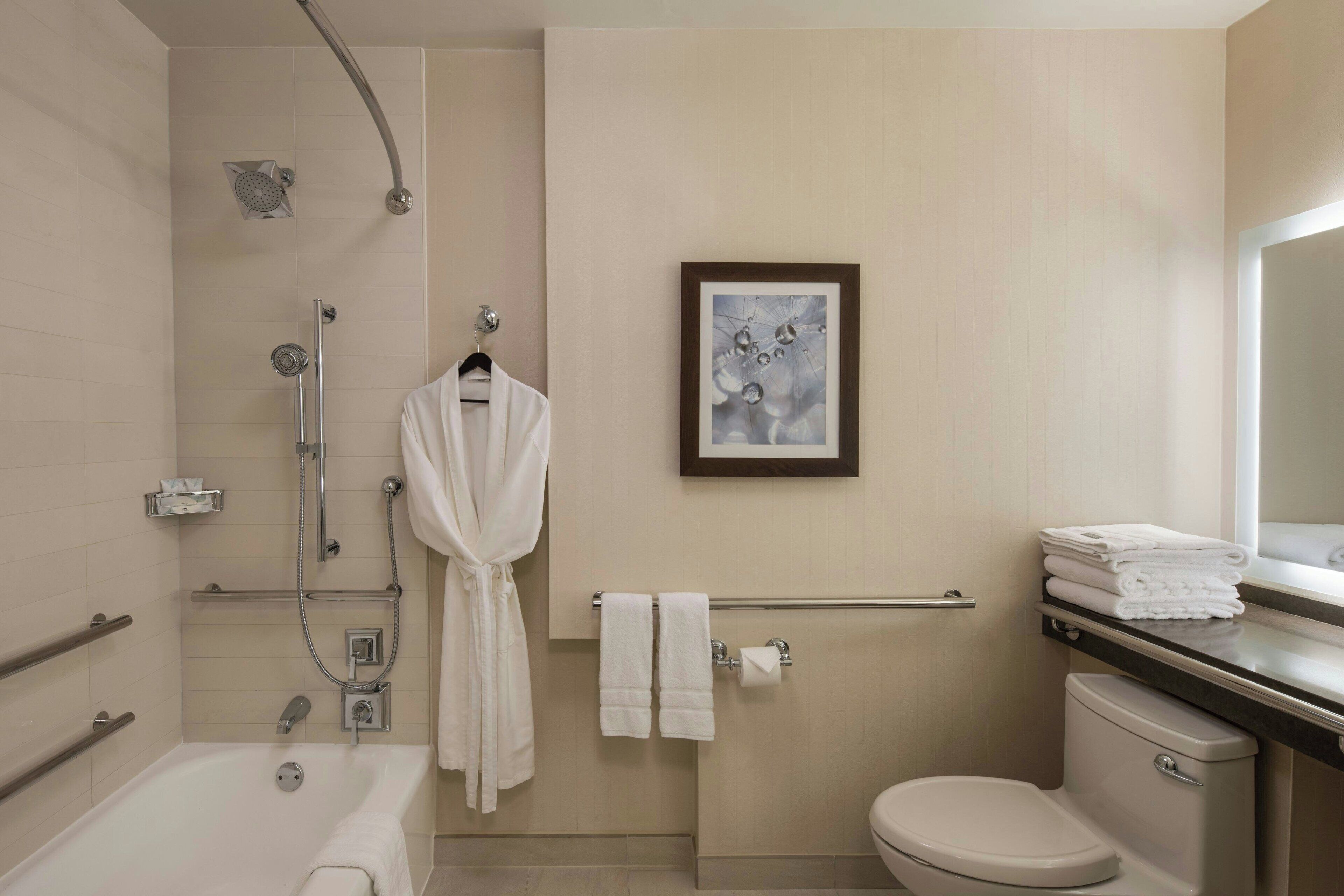 A modern bathroom with a bathtub, shower, toilet, and a towel rack.