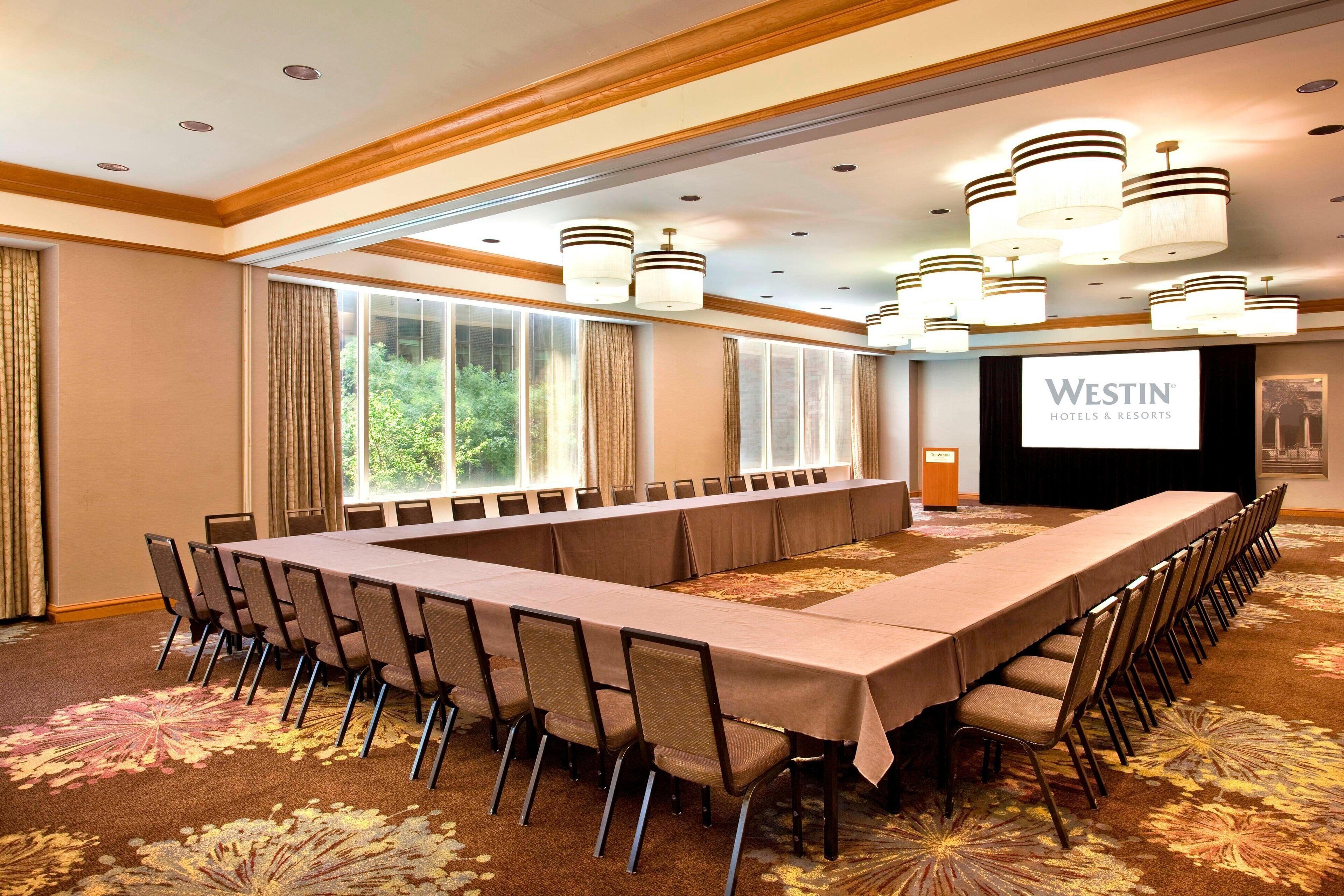 A conference room with a long table and chairs, large windows, and a Westin Hotels & Resorts sign.