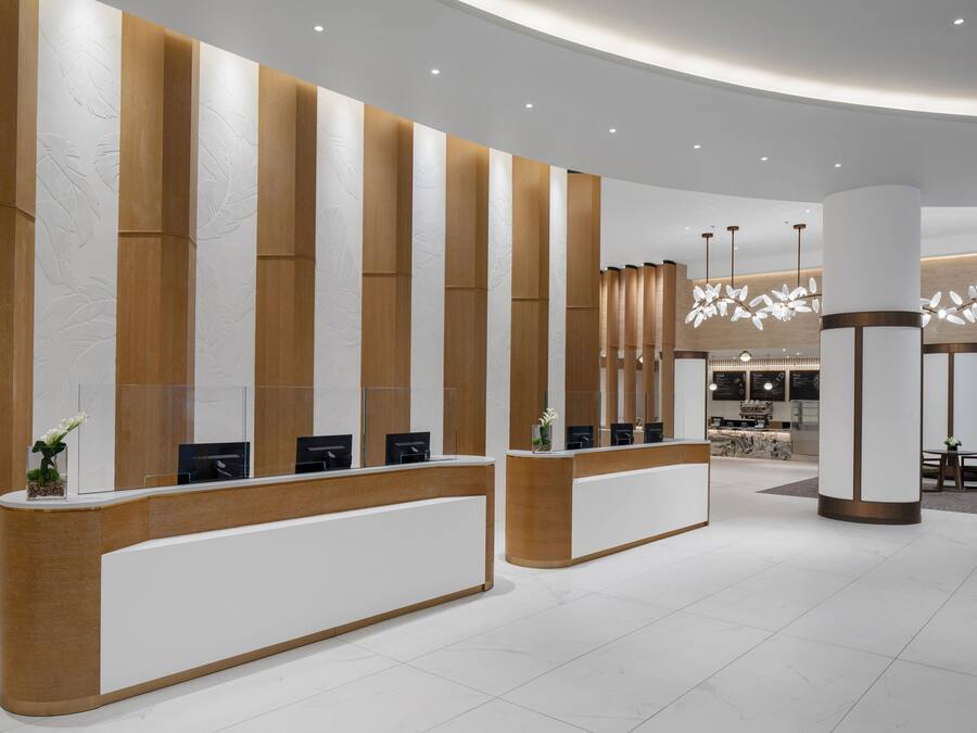 Een receptiegedeelte met een modern design, bestaande uit een gebogen receptiebalie, een zithoek en een decoratieve verlichtingsarmatuur.