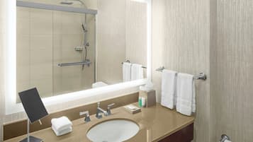 A modern bathroom with a large mirror, a sink, and a shower.
