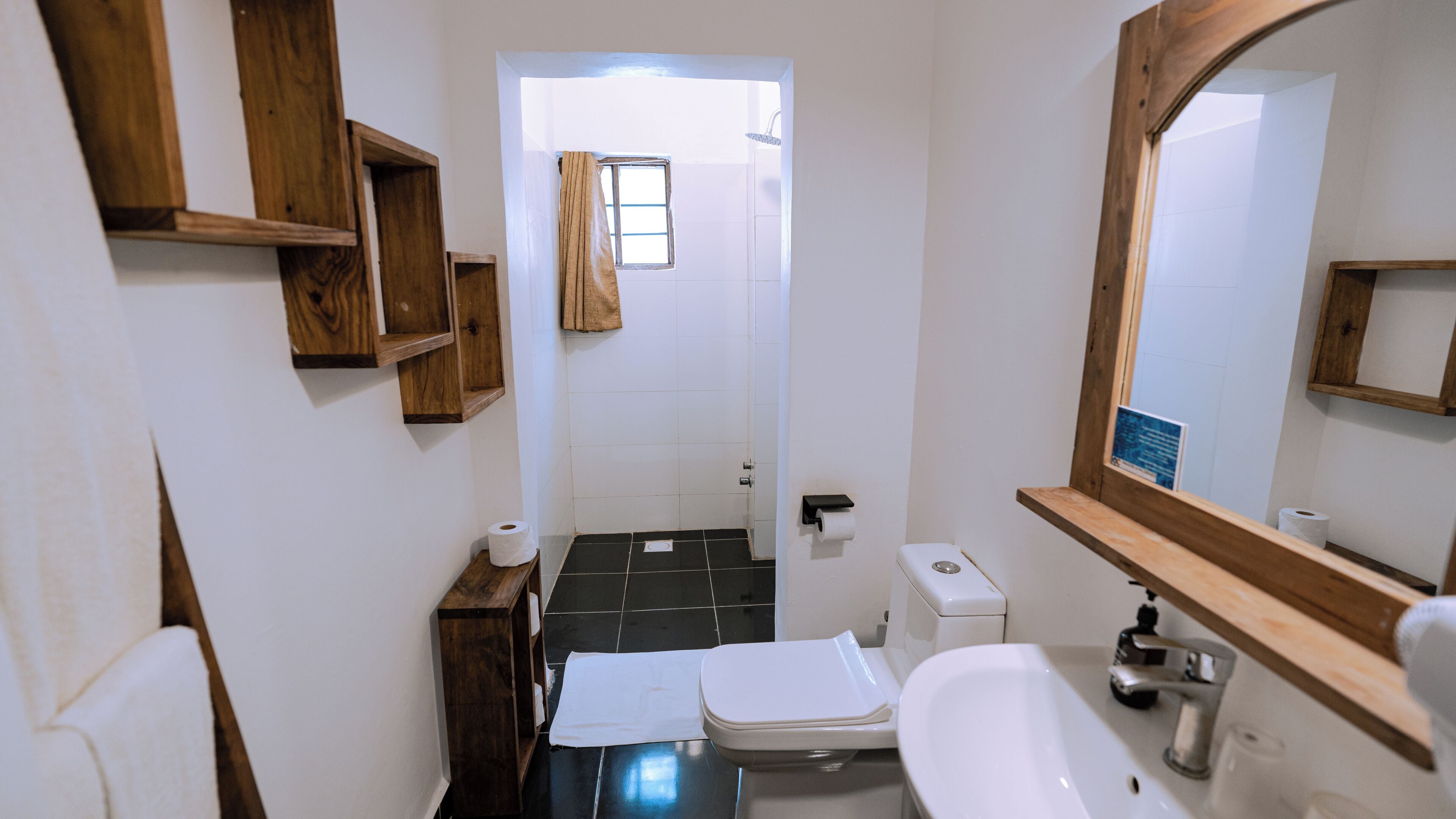 A compact bathroom with a toilet, sink, and wooden shelves.