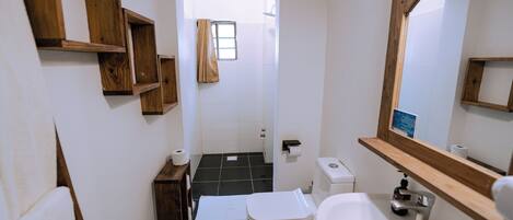 A compact bathroom with a toilet, sink, and wooden shelves.