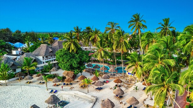 A resort with multiple thatched-roof structures, a swimming pool, and palm trees. - Paradise Beach Resort (Uroa)