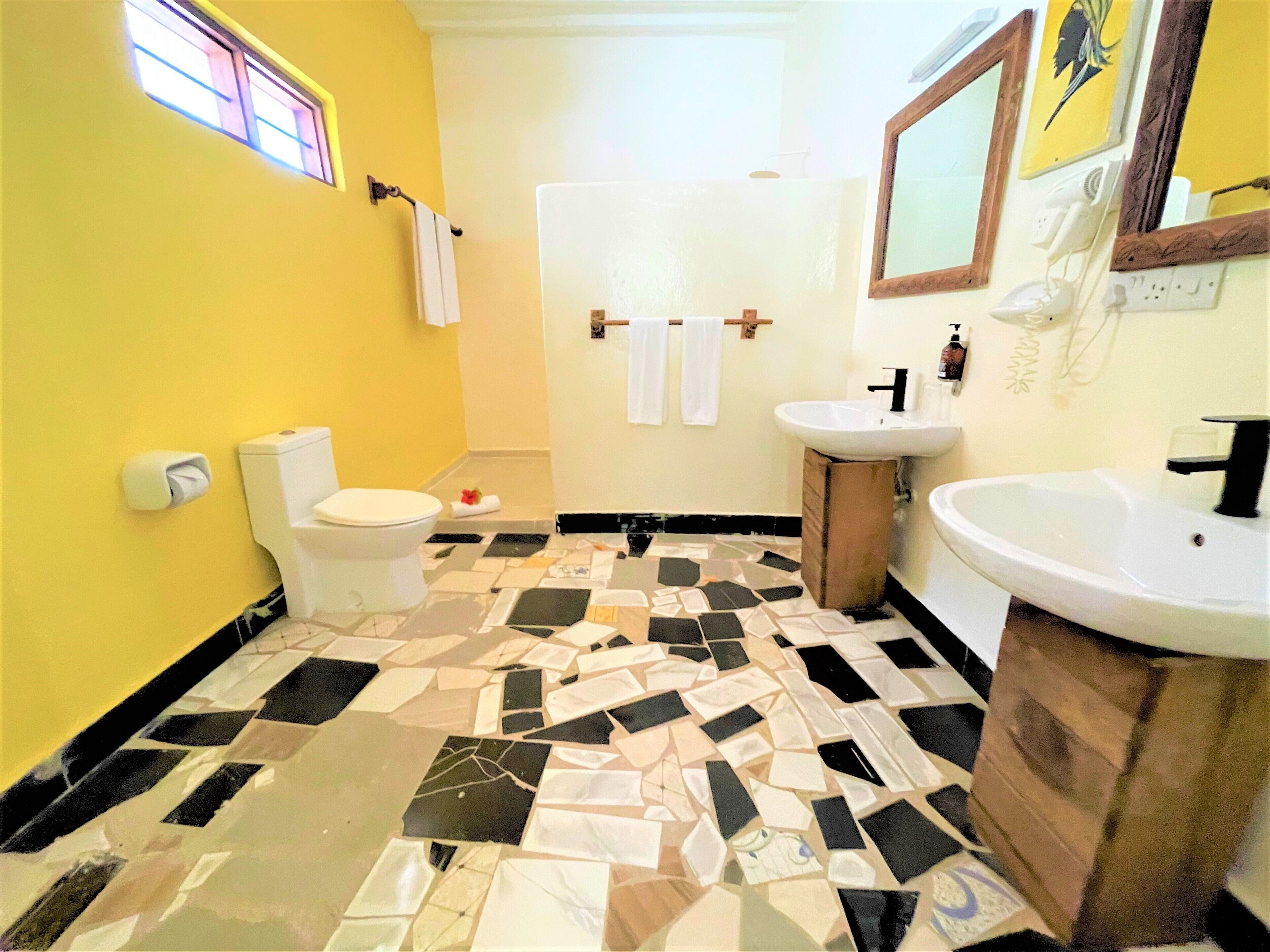 A bathroom with a yellow wall, a toilet, a sink, and a mirror.