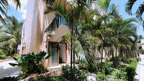 A hotel entrance with a covered patio, palm trees, and a clear sky. - Paradise Beach Resort (Uroa)