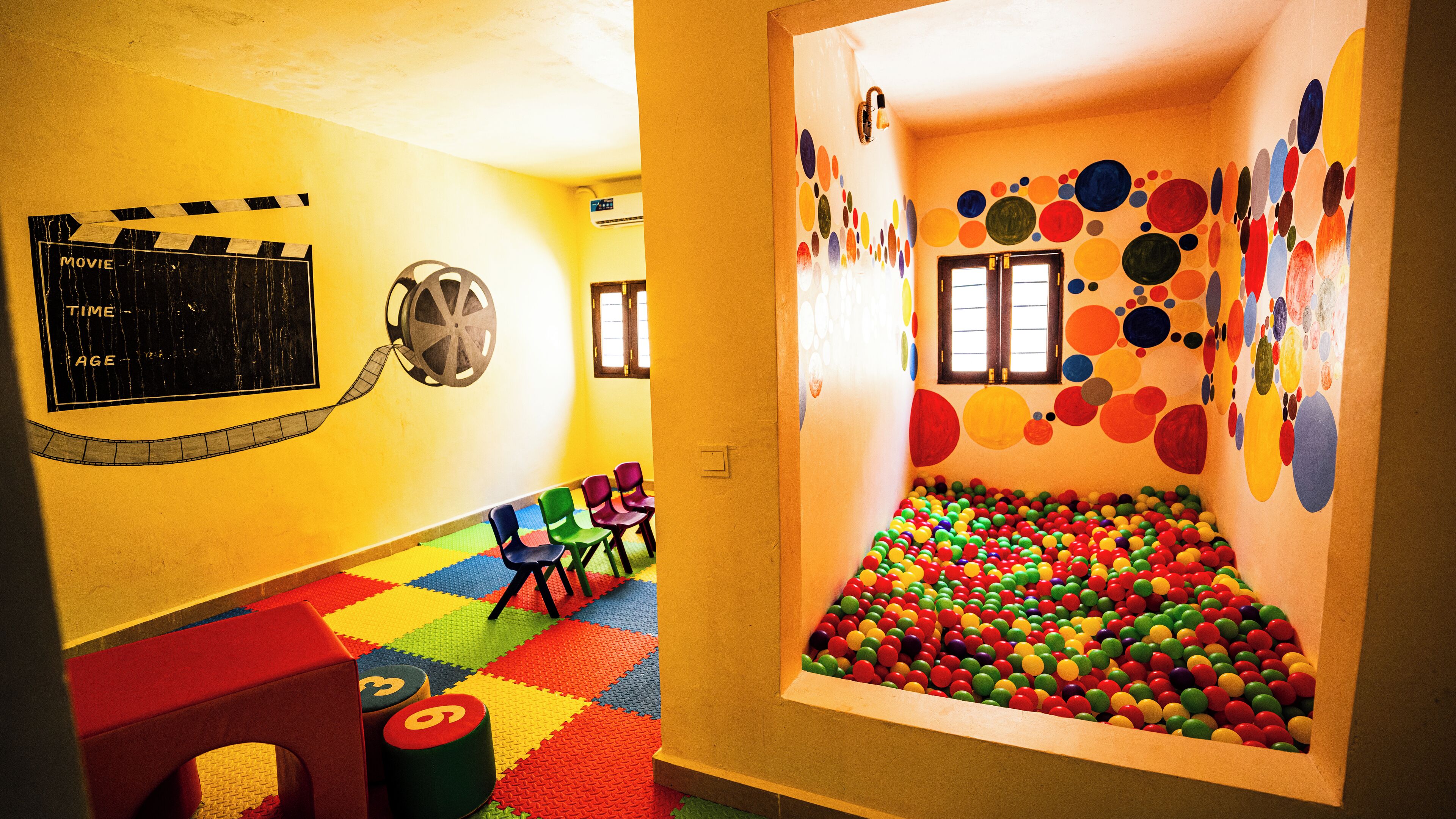 Uma sala de brincadeiras com bolas coloridas, uma fita de filme e um relógio.