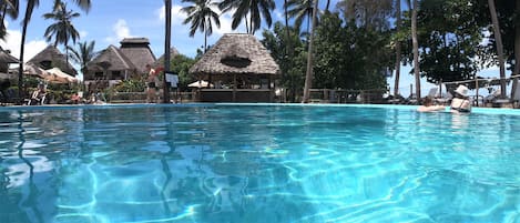 Una piscina al aire libre, sombrillas, tumbonas