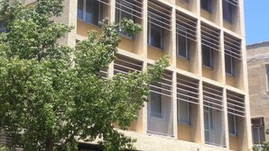 A multi-story building with a beige facade, large windows, and a tree in front. - 27 Montefiore TLV (Tel Aviv)