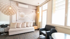 A modern living room with a sofa, chairs, a dining table, and a large window. - 27 Montefiore TLV (Tel Aviv)