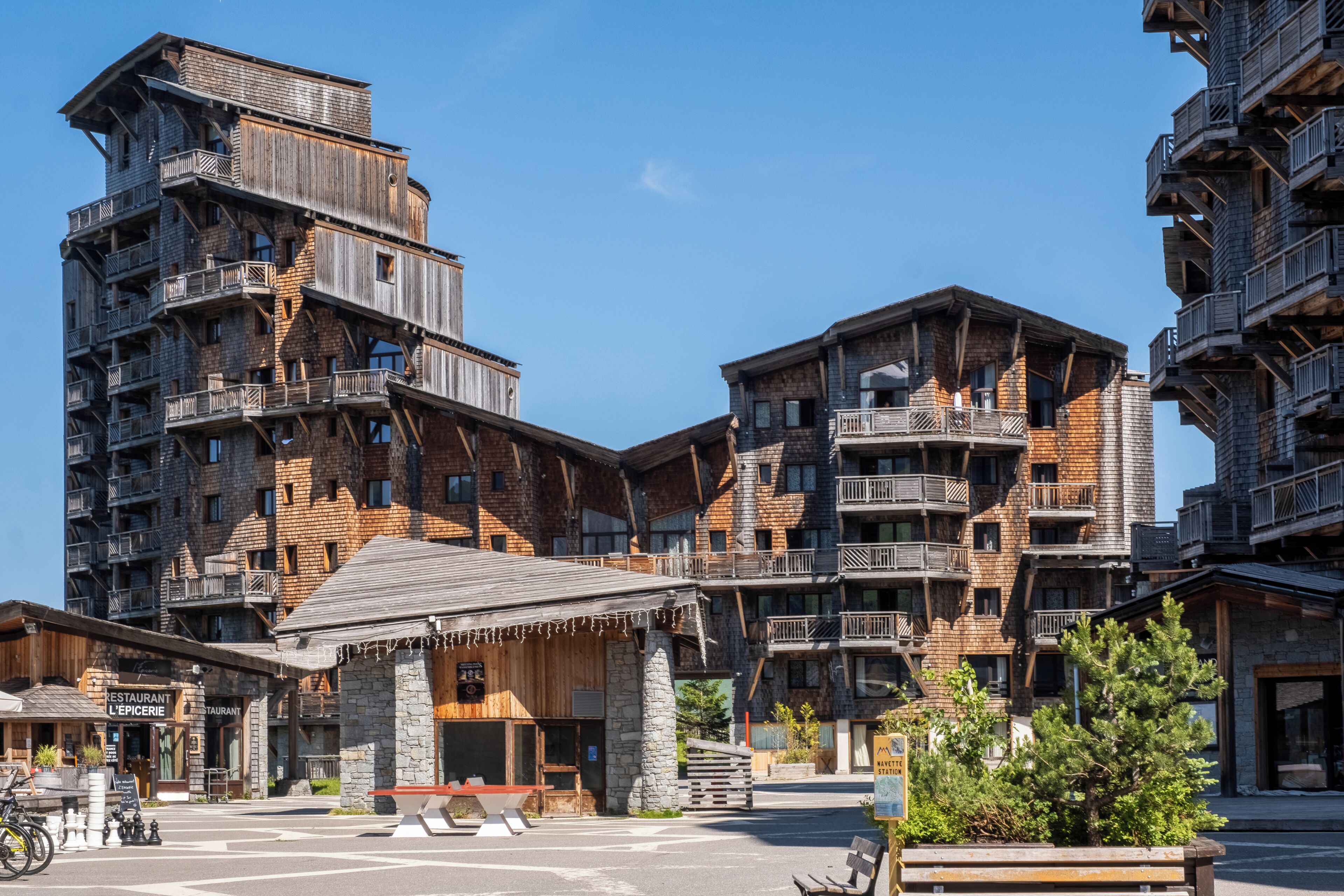 A multi-story building with balconies, a stone facade, and a small outdoor seating area.