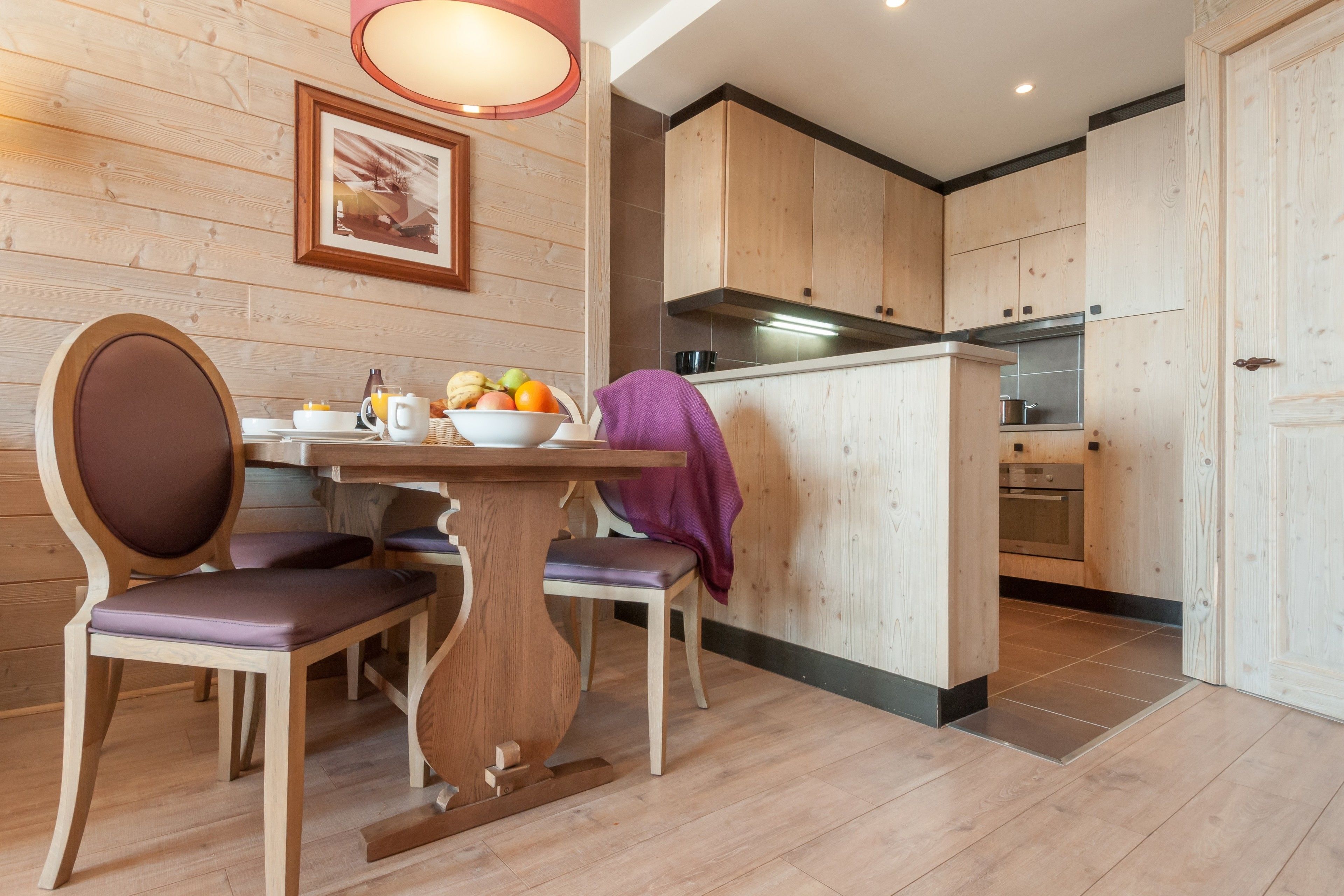 Cocina con paneles de madera, una mesa de comedor, sillas y una isla visible con estufa.