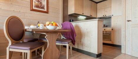 Cocina con paneles de madera, una mesa de comedor, sillas y una isla visible con estufa.