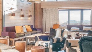 A modern living room with wooden floors, a large window with a view, and a black pendant lamp. - Résidence Pierre & Vacances Premium L'Amara (Avoriaz)