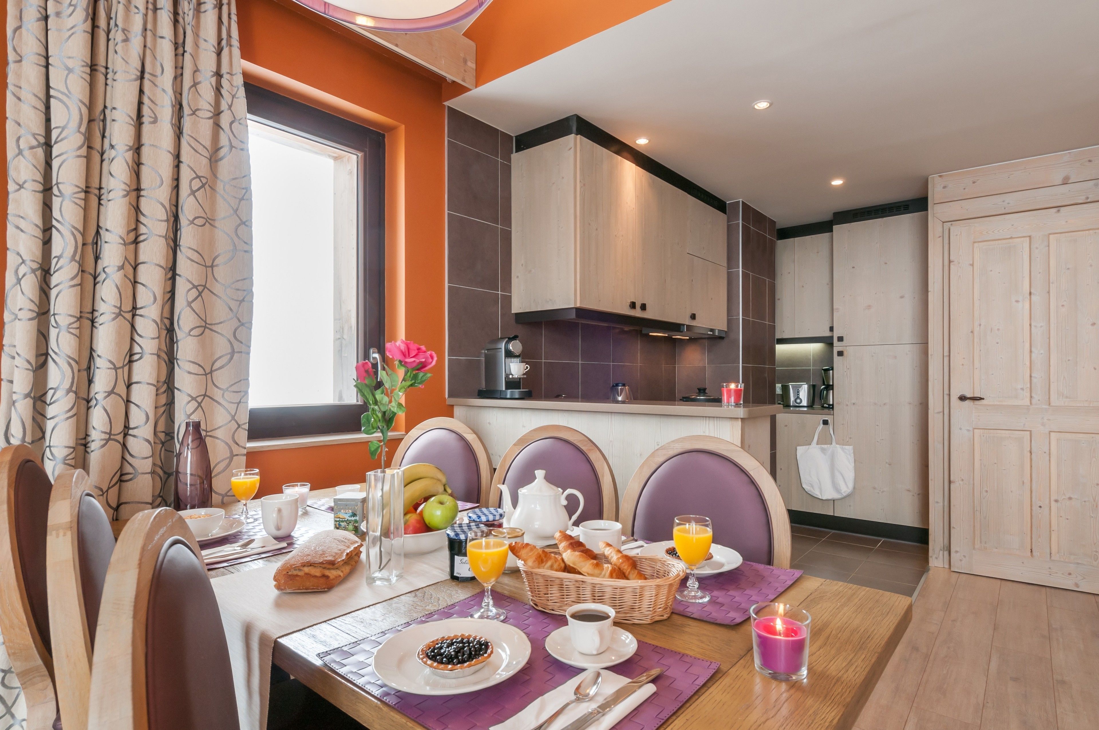 A breakfast setup with a table, chairs, and a kitchen in the background.