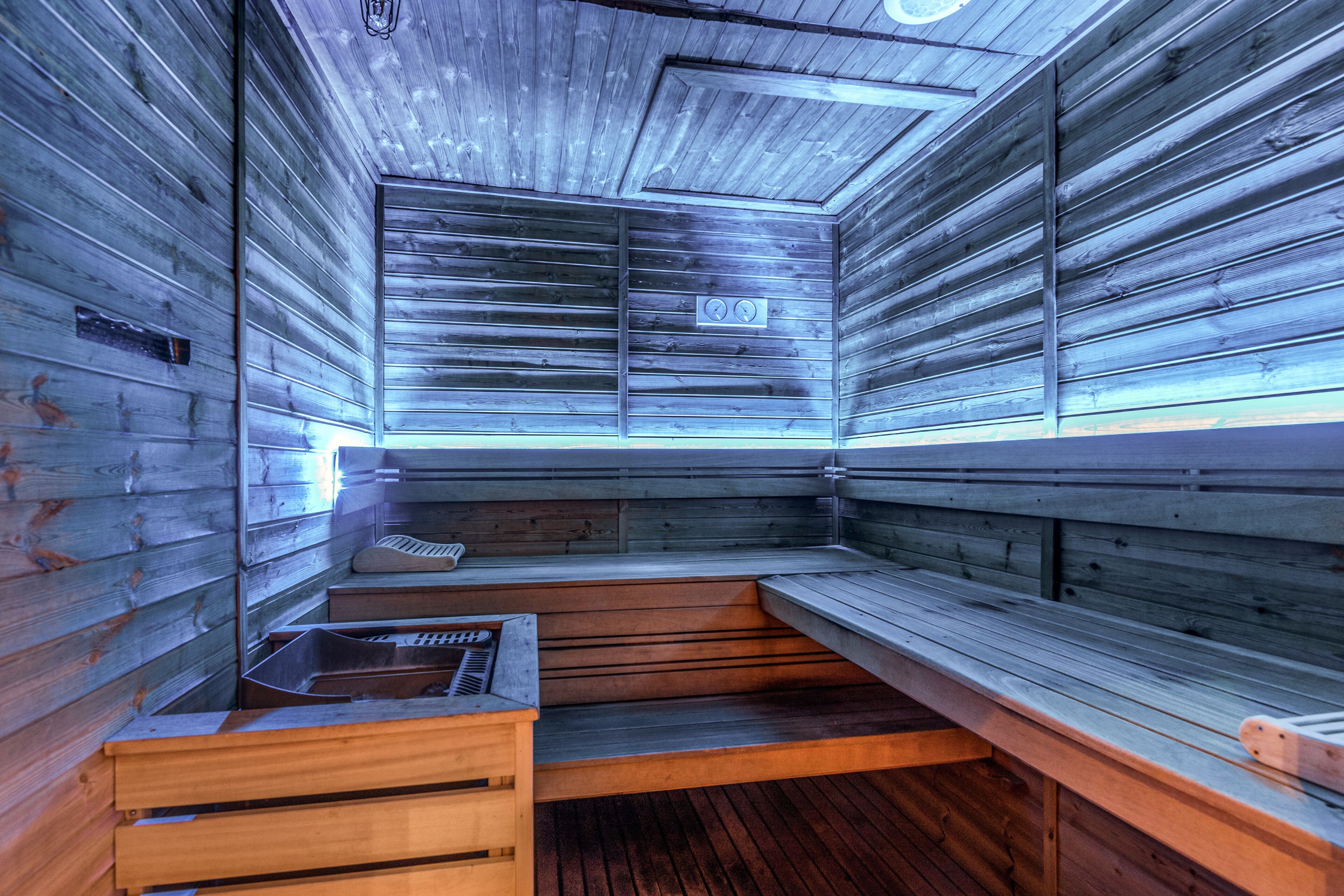 Een sauna met houten banken en een bank met een wastafel.