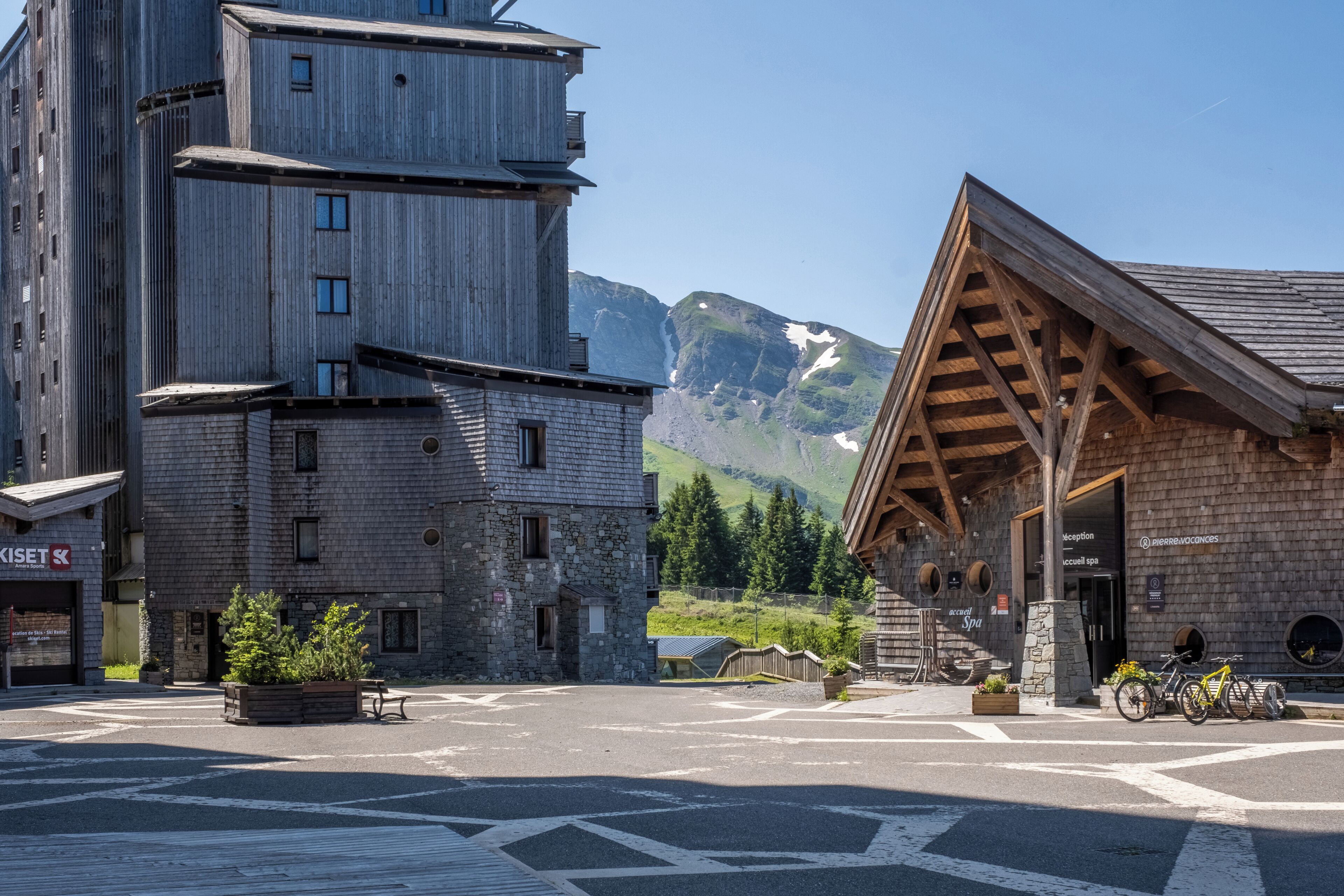 A mountain lodge with a stone facade, wooden exterior, and a ski lift in the background.