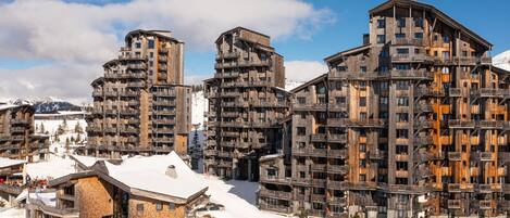 A modern ski resort with multi-story buildings featuring balconies and wooden facades.