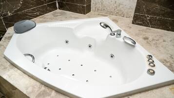 A modern bathroom with a freestanding bathtub, a handheld showerhead, and a built-in faucet.