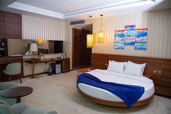 A hotel room with a large bed, a desk, a chair, and a television.