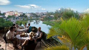 A group of people dining at an outdoor table with a view of a river and surrounding buildings. - Siem Reap Riverside Hotel (Siem Reap)