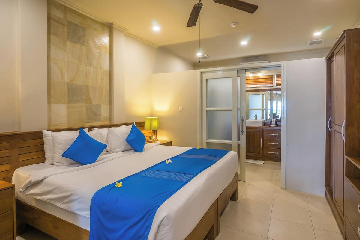 A hotel room with a bed, a nightstand, a lamp, a wardrobe, and a sliding door to the bathroom.