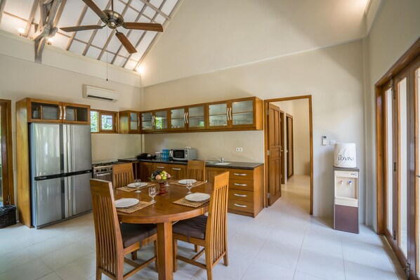 Una cocina amplia con armarios de madera, un refrigerador de acero inoxidable y una zona de comedor preparada para cuatro.