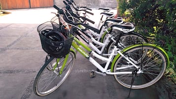 A bicycle with a basket and a water bottle attached, parked on a paved surface.