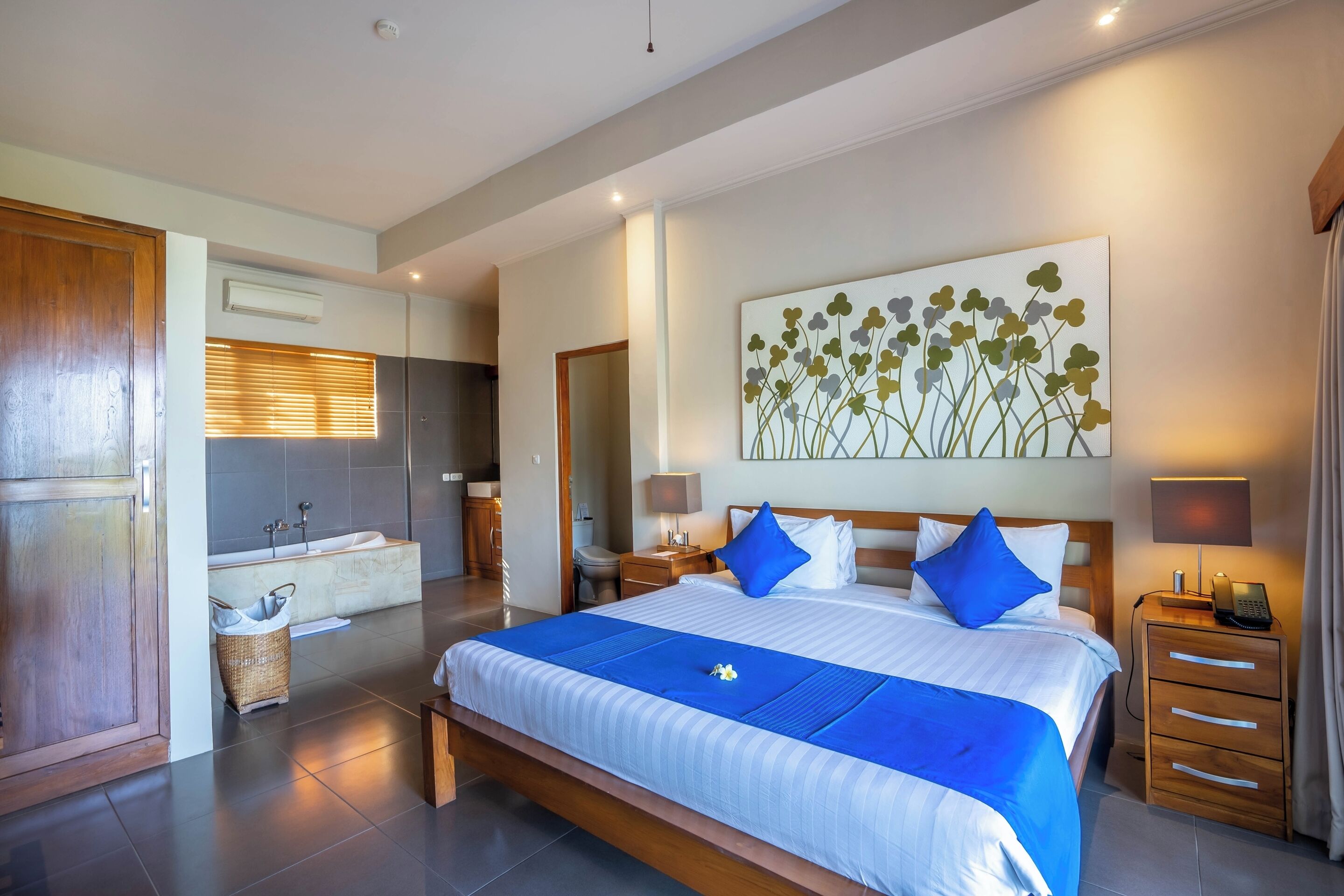 Una habitación de hotel moderna con una cama grande, un baño con bañera y un cuadro en la pared.