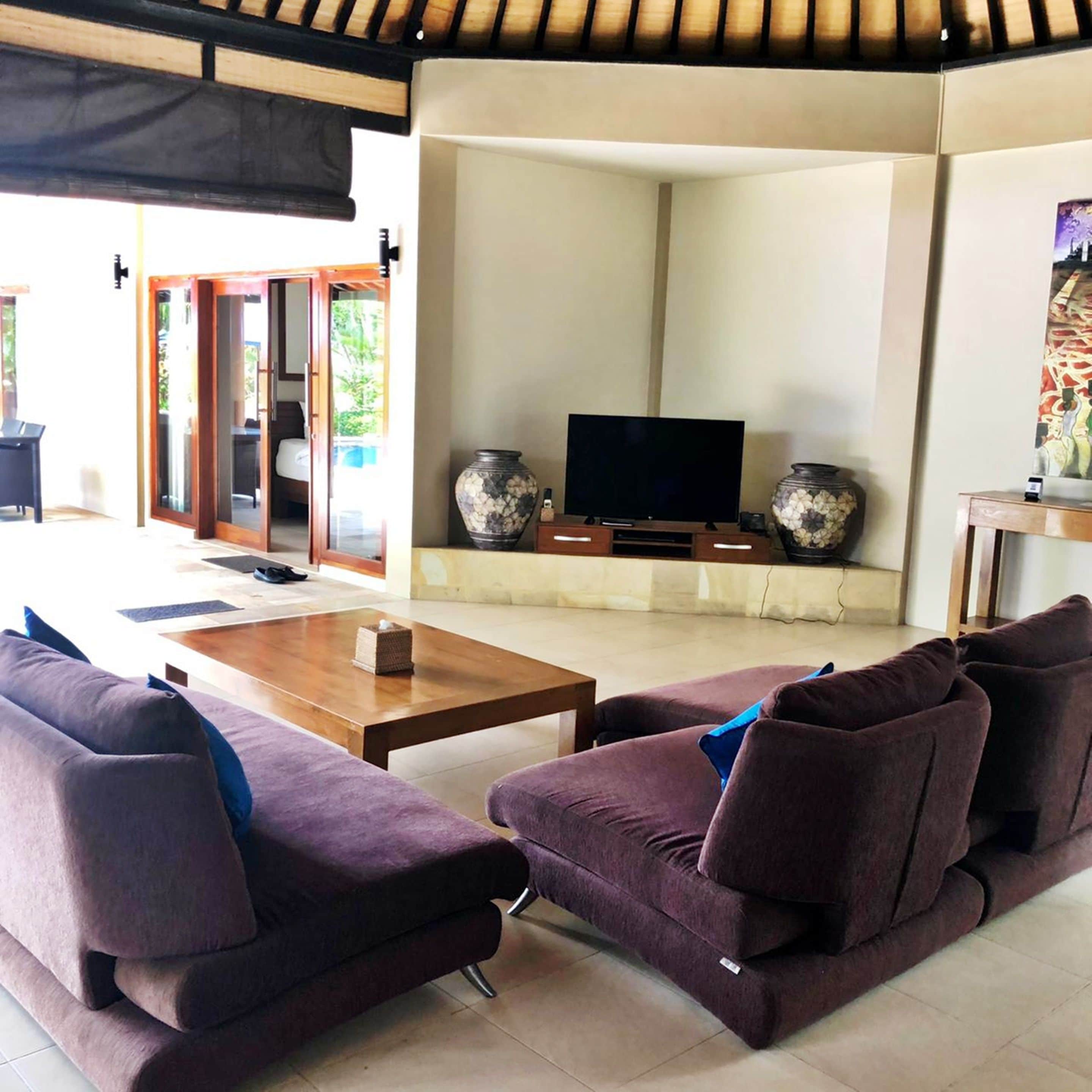 A living area with a sofa set, a coffee table, a flat-screen TV, and decorative vases.