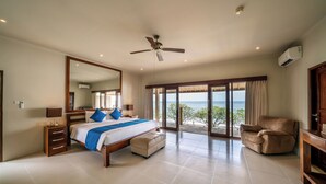 A spacious bedroom with a large bed, a ceiling fan, a view of the ocean, and a balcony. - The Lovina (Buleleng)