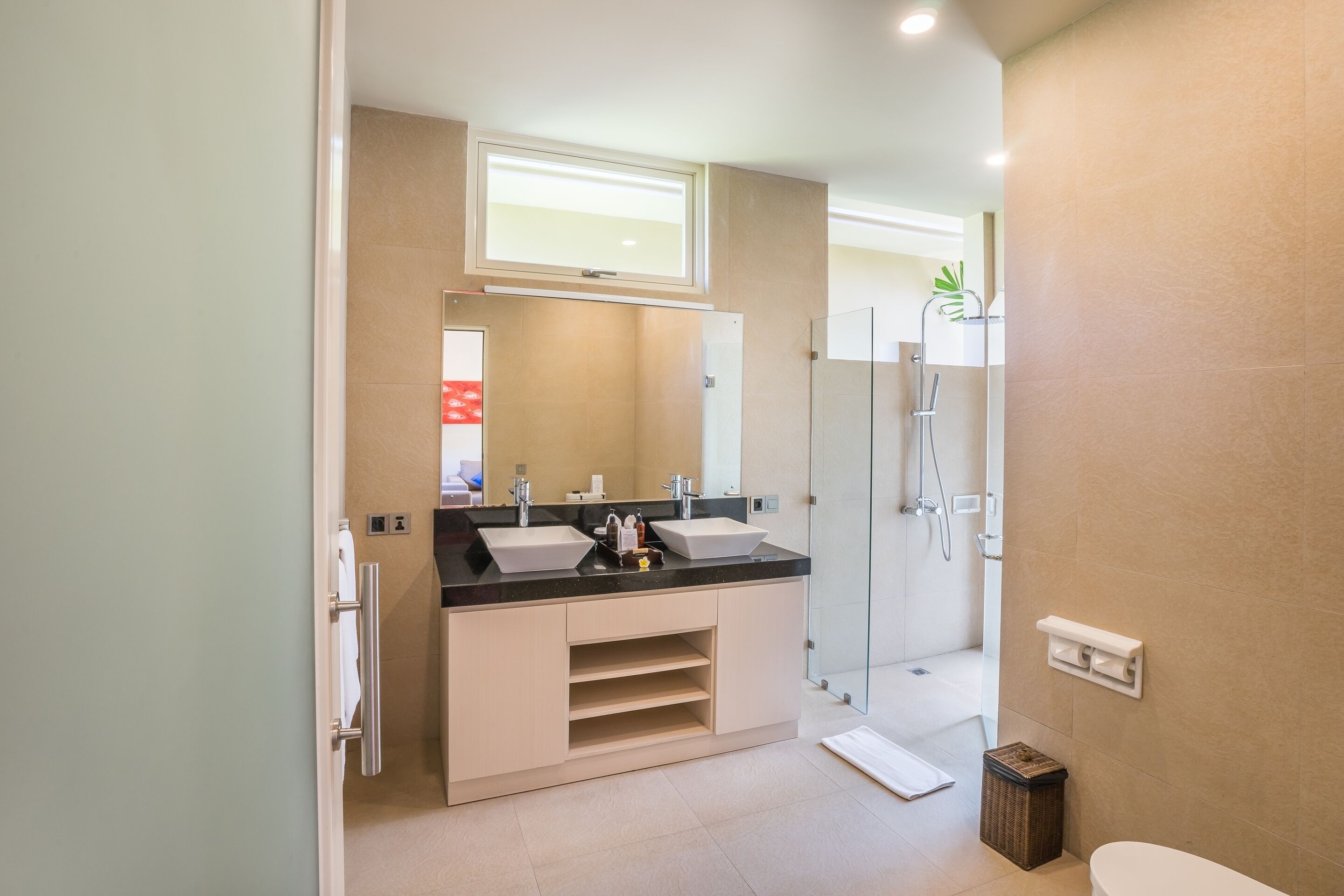 A modern bathroom with two sinks, a shower, and a toilet.