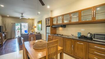 A modern kitchen with wooden cabinets, a dining area with a wooden table and chairs, and a ceiling fan.
