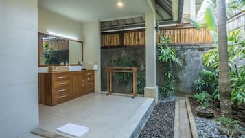 A modern bathroom with a wooden vanity, a large mirror, and a small table.